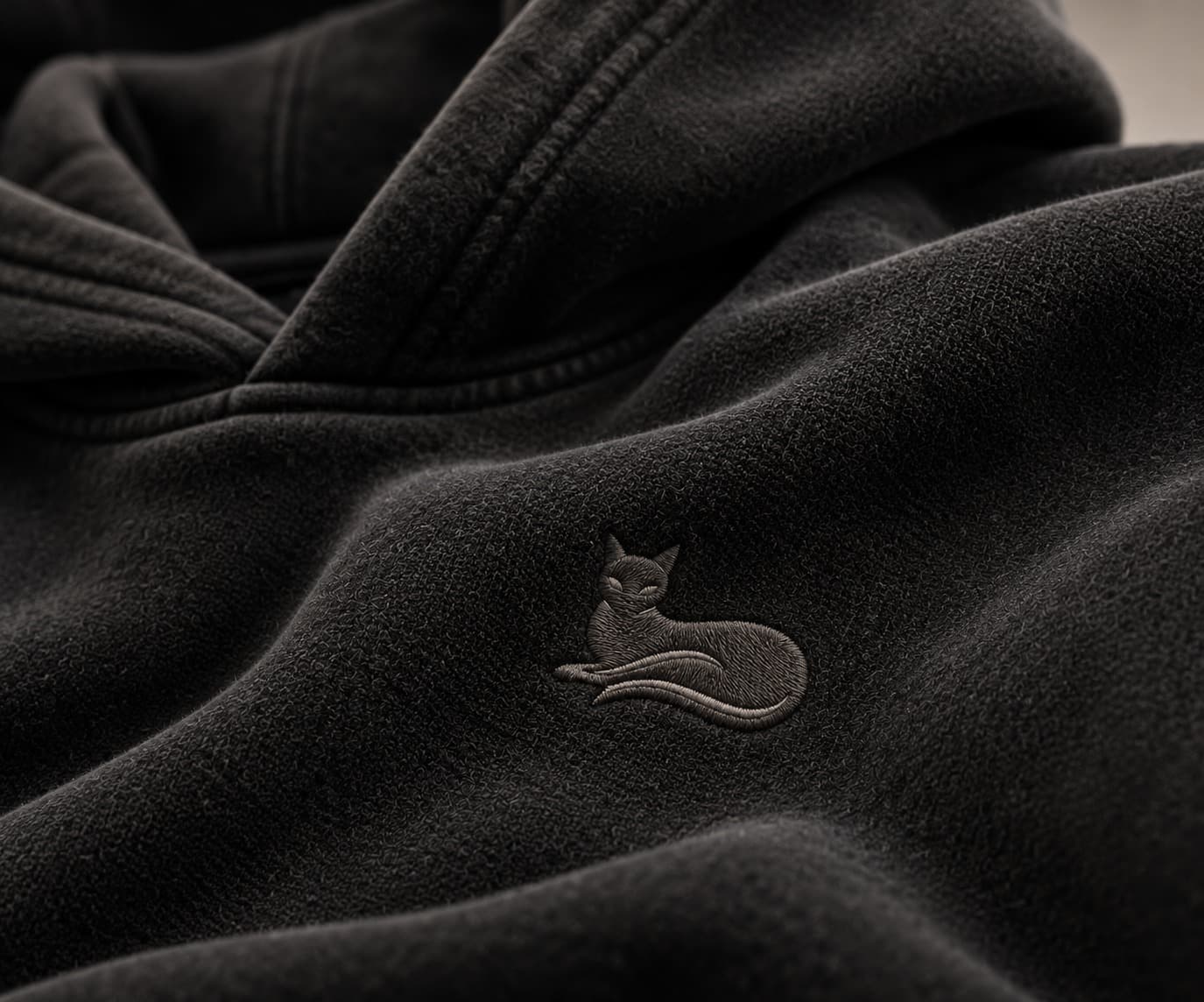 Close-up of tonal embroidered cat logo on the chest